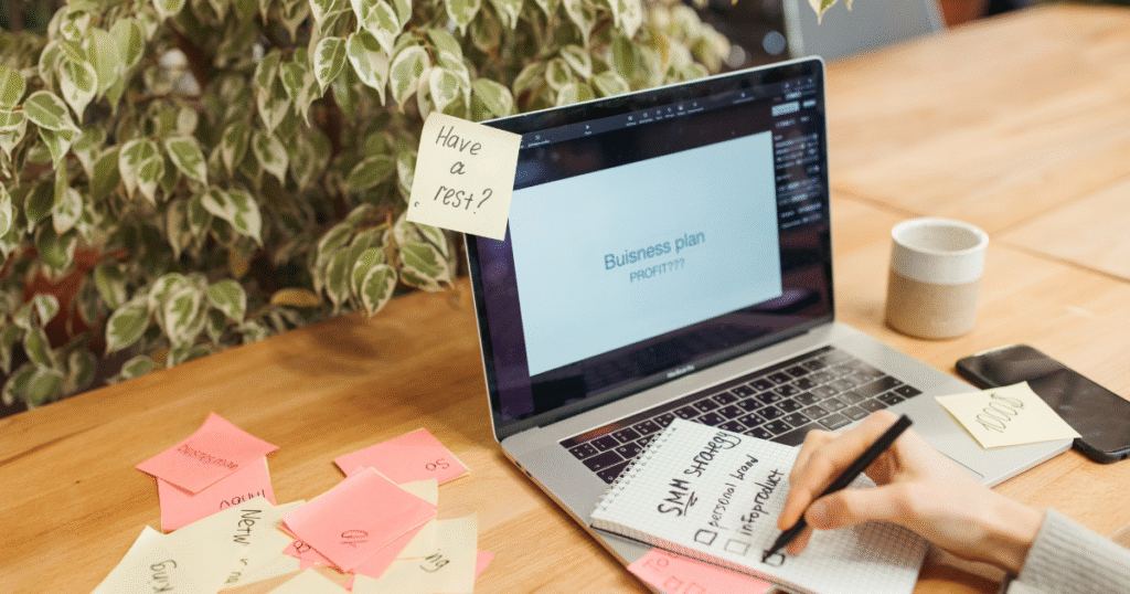 work with me on momentum builder, a woman writing with a business plan on the laptop screen
